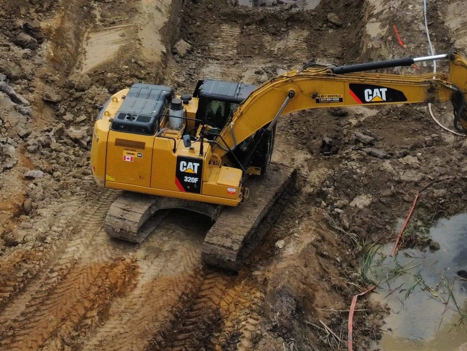 CAT 320 excavator digging a holding pond on a farm job site near Paris, Ontario