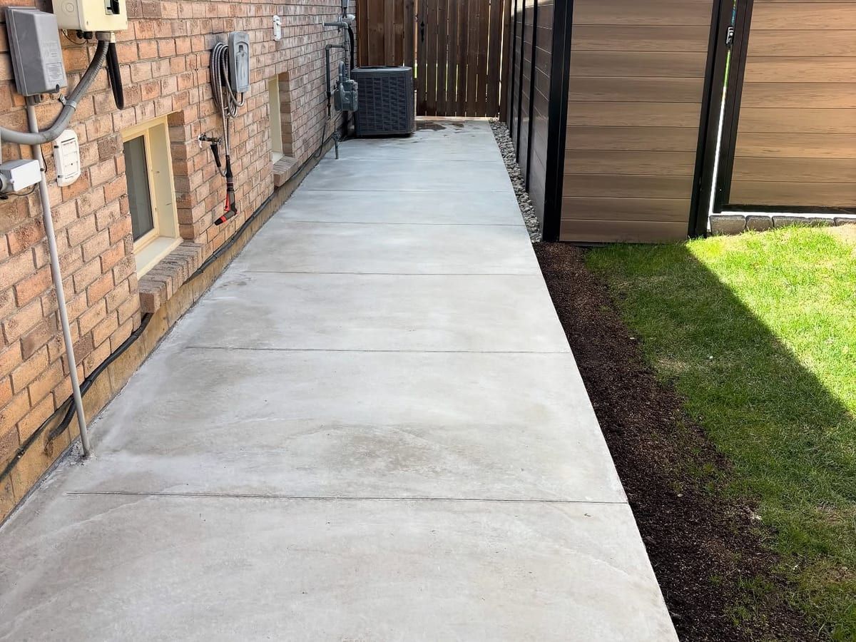 Broom-finish concrete side walkway running along a brick house